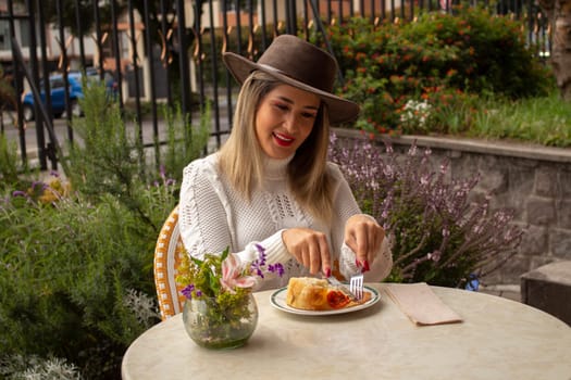 beautiful blonde woman cutting a focaccia with a fork and a knife. High quality photo