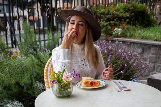 beautiful blonde woman in a hat pleasingly savoring a piece of focaccia. High quality photo