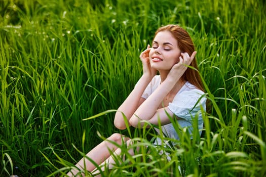 cute, happy woman sitting in tall grass on a sunny day in a light dress. High quality photo