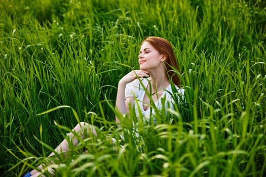 cute woman in summer high grass sits in a light dress. High quality photo