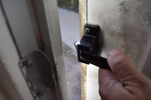 Hand Opening the Latch on a Dirty Door. High quality photo