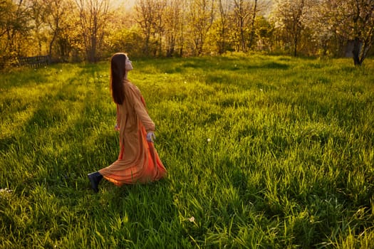 a joyful woman runs through a green field with her hands behind her back, enjoying a warm summer day and nature during the sunset. Horizontal photography in nature. High quality photo