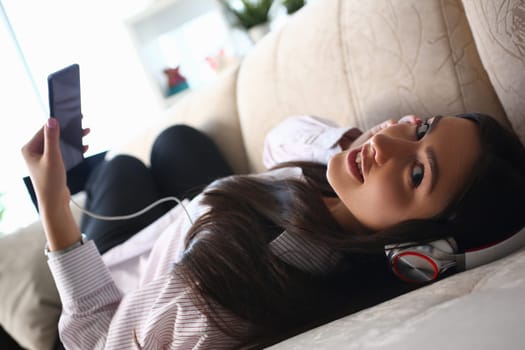 Relaxed woman listening to music on headphones at home. Mobile apps for music concept