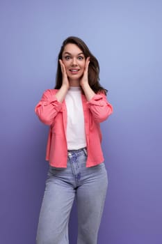 shy brunette woman with dark hair below her shoulders posing against a studio background.