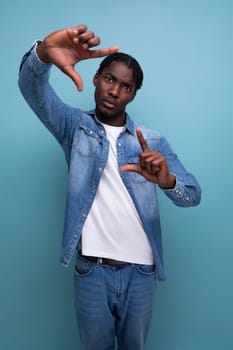 portrait of a young american man with dreadlocks in a denim jacket taking a photo.