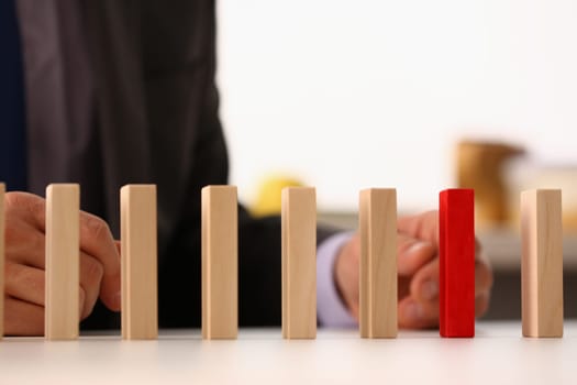 Businessman hand selects red wooden block on table. Business planning risk management solution and leadership strategy