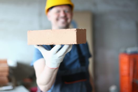 Master builder man holding red brick at construction site. Brick laying master concept