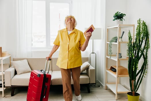 Happy senior woman with passport and travel ticket packed a red suitcase, vacation and health care. High quality photo