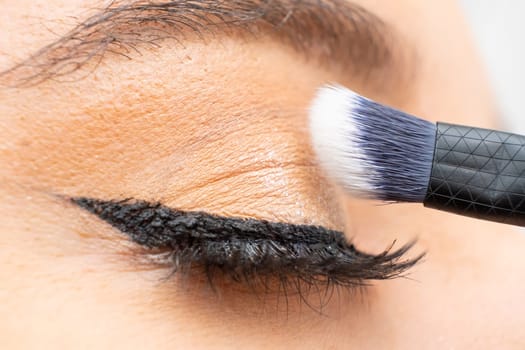 Close up applying shadow with a brush to eyelid. Perfect makeup.