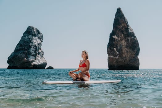 Close up shot of beautiful young caucasian woman with black hair and freckles looking at camera and smiling. Cute woman portrait in a pink bikini posing on a volcanic rock high above the sea