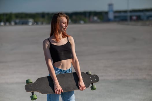 Young caucasian woman holding a long board outdoors