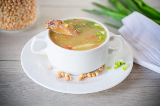 dried pea soup in a plate with herbs, on a wooden table.