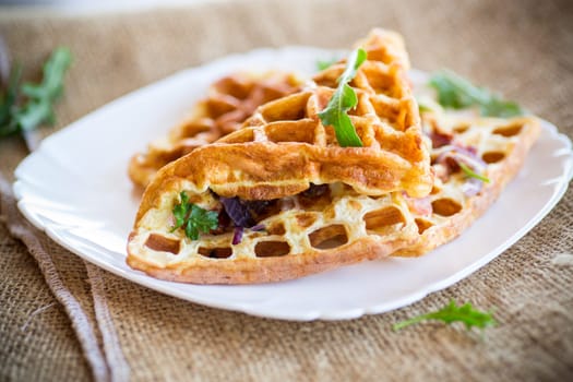 Egg omelette stuffed with onions and herbs, fried in the form of waffles, on a wooden table