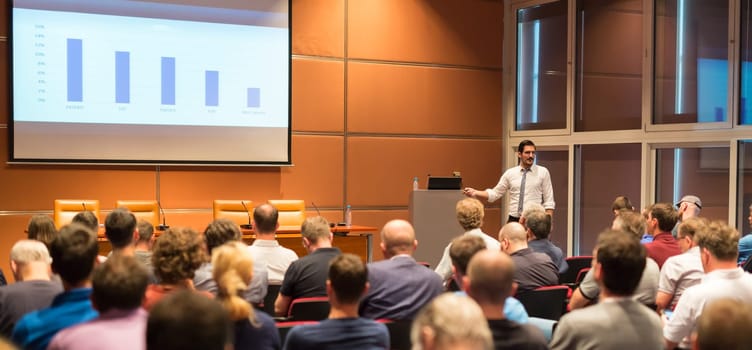 Speaker giving talk in conference hall at business event. Audience at the conference hall. Business and Entrepreneurship concept. Panoramic composition.