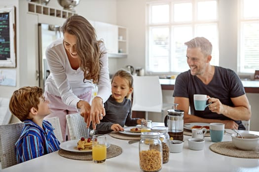 Making sure her family is well fed. a family having breakfast together