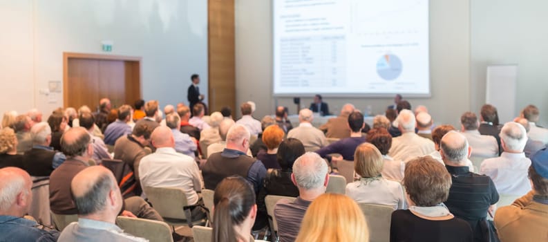 Speaker Giving a Talk at Business Meeting. Audience in the conference hall. Business and Entrepreneurship. Panoramic composition.