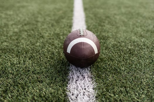 American football ball on green grass field background