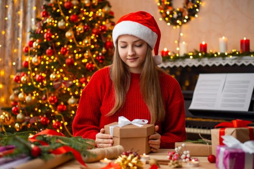 Pretty young girl holding present box, sitting in beautiful room, full of lights and Christmas decoration