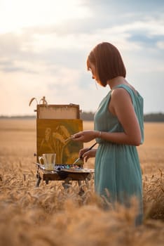 Young female painter working in the field on a summer day during sunset