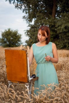 Red-headed girl artist creates work of art in the field on a warm summer day