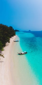 Koh Kradan Island with a white tropical beach and turqouse colored ocean. Drone aerial view at the beach with longtail boat