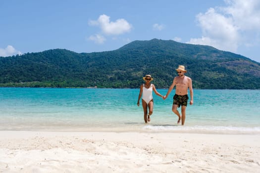 Couple on the beach of Koh Lipe Island Thailand, a tropical Island with a blue ocean and white soft sand. Ko Lipe Island Thailand. men and women relaxing on the beach looking out over ocean