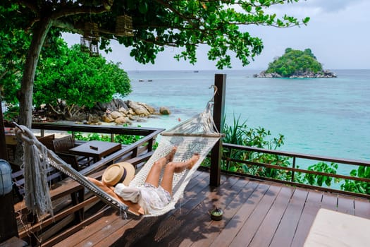 Asia women on vacation at Koh Lipe Island Thailand relaxing at a hammock, a tropical Island with a blue ocean and white soft sand. Ko Lipe Island Thailand