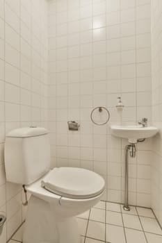 a white toilet in a small bathroom with tiled walls and floor to the right, there is a mirror on the wall