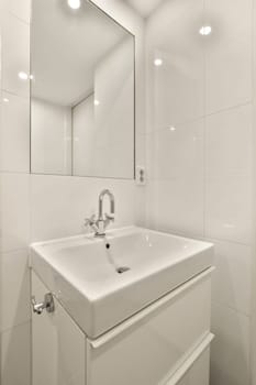 a white bathroom with a mirror above the sink and light fixtures on the wall in the room is very clean