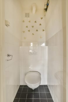 a white toilet in a bathroom with black and white tiles on the floor, walls, and ceiling above it