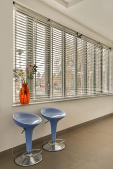 a living room with two chairs and a vase on the window sier in front of the couch is blue