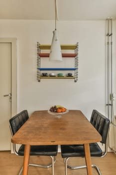 a dining table and chairs in a room with white walls, wood flooring and shelves on the wall above it