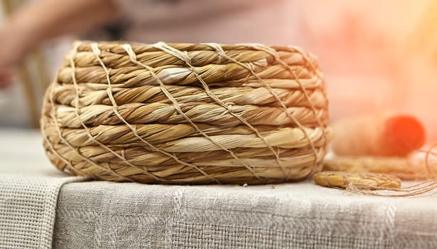 Weaving in progress, a plate of grass. Basket woven from grass. Rural still life.