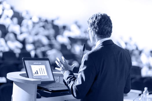 Speaker at Business Conference with Public Presentations. Audience at the conference hall. Entrepreneurship club. Rear view. Horisontal composition. Background blur.