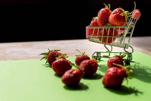 Little shopping cart filled with raw delicious strawberries. Concept shot symbolizing buying healthy food or ordering online