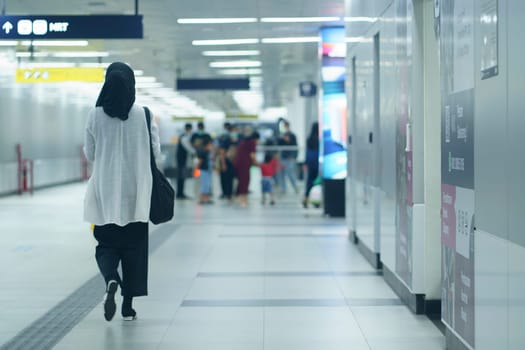 A hijab woman walking to the entry gate at MRT Jakarta Station, Indonesia. April 20, 2023. Publice service photography.