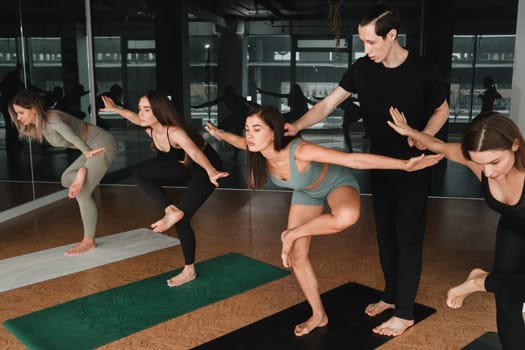 a group of girls do yoga in the gym under the guidance of a coach.