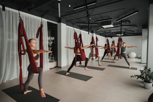 A group of women play sports on hanging hammocks. Fly yoga in the gym.