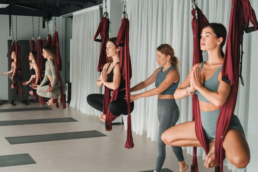 A group of women with a coach are engaged in sports in hanging hammocks . Fly yoga in the gym.