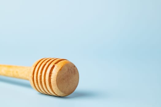 Closeup of a honey dipper on blue background for kitchen utensils concept.