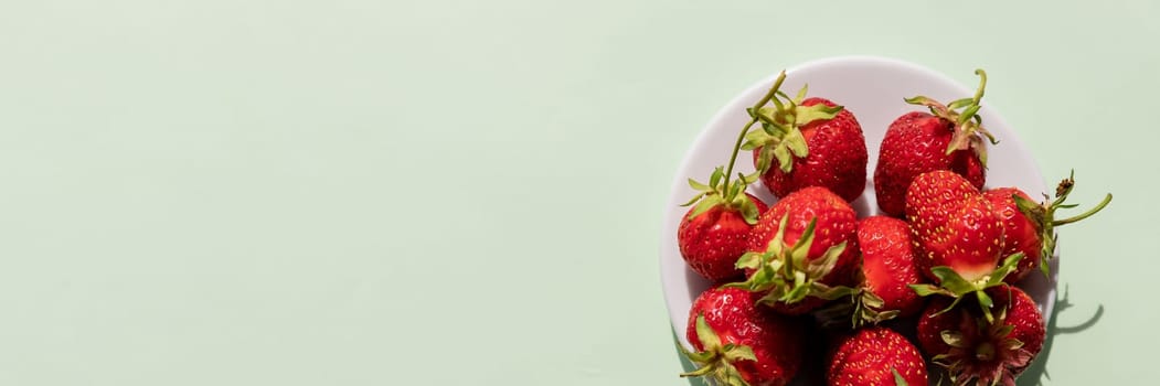 Heap of fresh strawberries in ceramic bowl on rustic white wooden background.