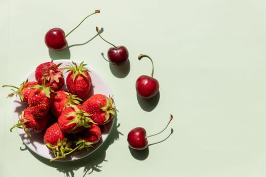 Heap of fresh strawberries in ceramic bowl on rustic white wooden background.
