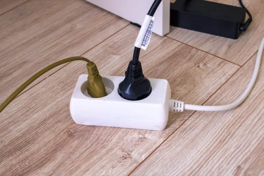 Extension cord with two sockets on the floor close up