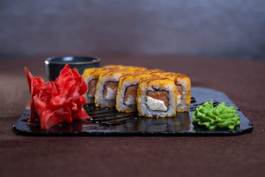 baked rolls with salmon and tender cheese with sauce on a black plate.