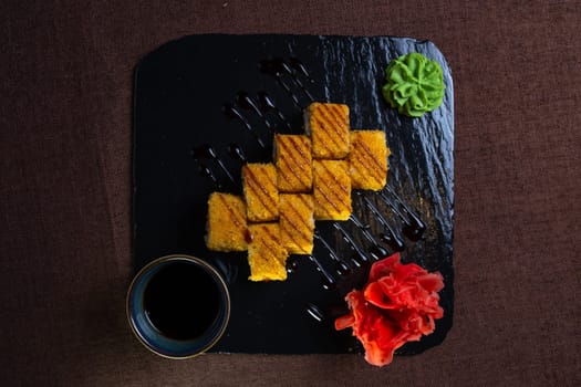 baked rolls with salmon and tender cheese with sauce on a black plate top view.