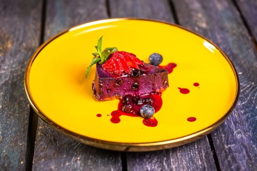 berry mousse with strawberries on a yellow plate.