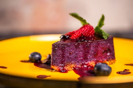 close-up of berry mousse with strawberries on a yellow plate.