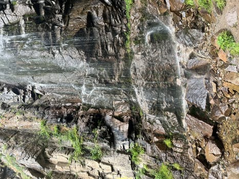 Waterfall on a stone cliff view on a summer day.