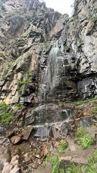 Waterfall on a stone cliff view on a summer day.