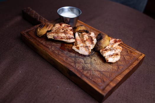 grilled chicken fillet with mushrooms on a wooden board.